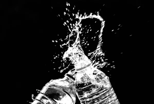Fresh pure water splashing out of bottle on black background. Selective focus and space for text.