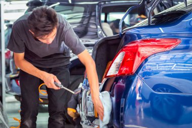 Asain adam arabayı temizliyor.