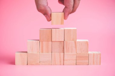 man hand building stack of wood cube building blocks