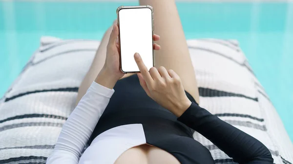 Woman in black and white swimsuit  holding mockup blank mobile phone