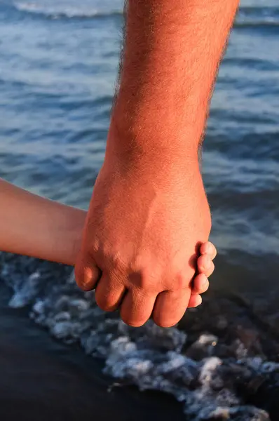 father and son holding hands on sea side