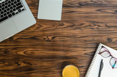 Laptop, kahve ve defter ahşap masada.