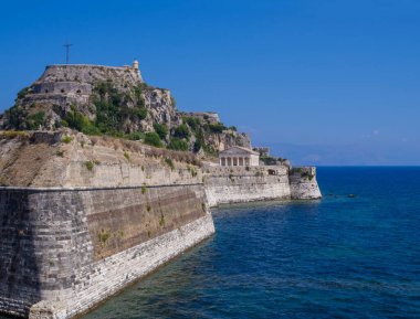 Ünlü turistik kent, saat kulesi ve tapınağı, Kerkyra şehri, Korfu, Yunanistan, yaz günü, mavi gökyüzü ve deniz geçmişi olan eski Venedik kalesi.