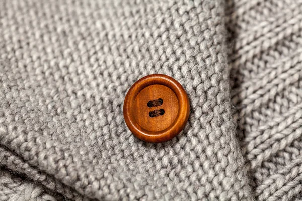 针织羊毛背景上的一个大的老式褐色钮扣 — 图库照片