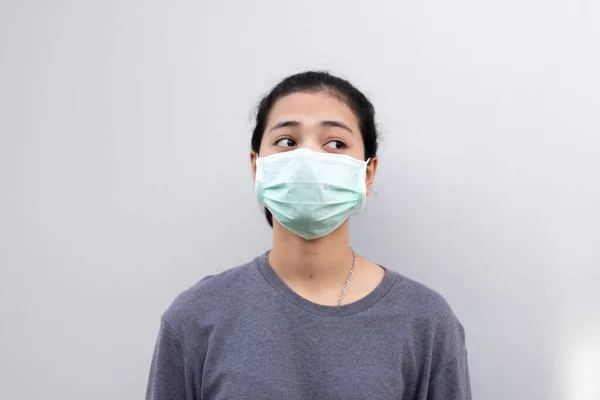 灰色の壁に立っている間若いアジアの女性は 医療面マスクを身に着けて — ストック写真