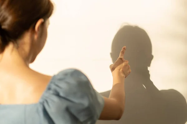 Woman is crazy, quarrel her shadow on the wall.