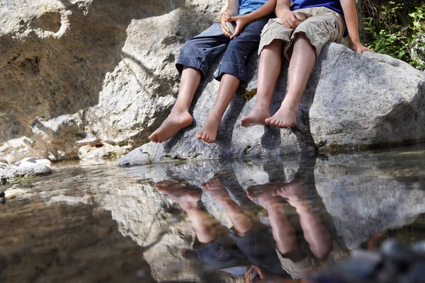 二人の少年 が川下の岩の上に座っている — ストック写真
