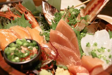 Japonya 'ya özgü otantik saşimi tabağı. Yeşil yapraklı çiğ balıklarla Japon yemek tarzı. Sinema tarzında hafif meşaleli.
