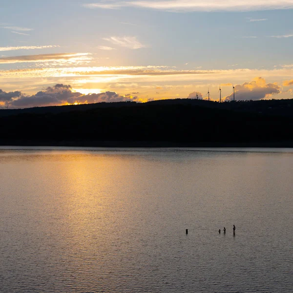 国立公園のイーフェルの日没時に穏やかな湖で3人が泳ぎ — ストック写真