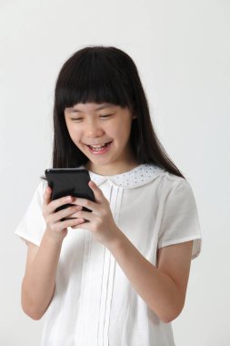 Asyalı küçük kız cep telefonuyla mesaj gönderiyor.