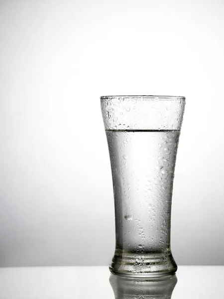 グレイバックグラウンドで飲料水でガラスのクローズアップビュー — ストック写真