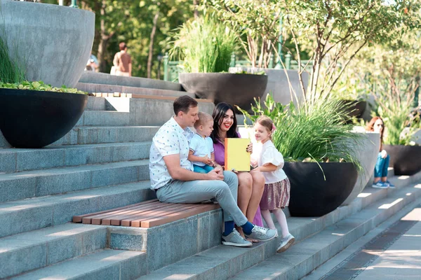 Happy Young Family Two Kids Sitting Park Reading Book — Stock Photo, Image