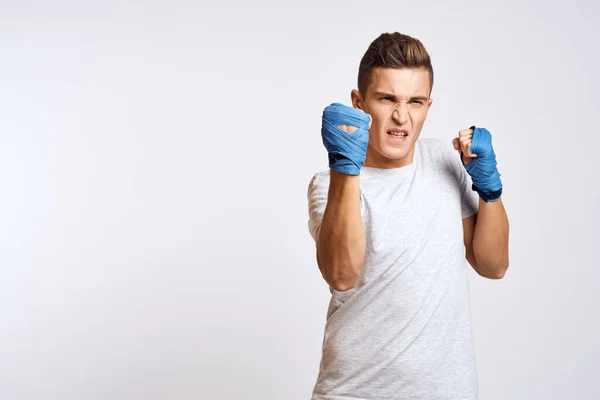 身披蓝色手套 身披运动衫的男性拳击手 在浅色背景下练习拳击 — 图库照片
