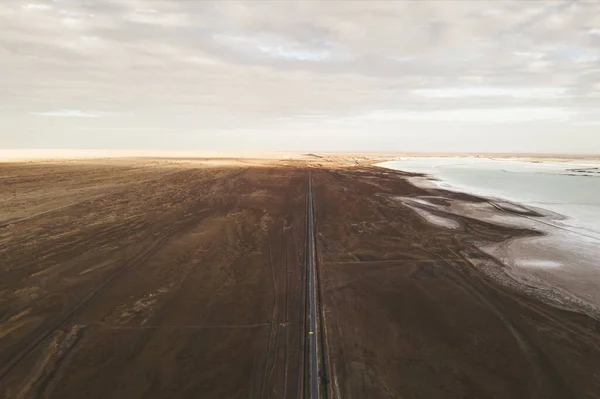 広い平地を背景にした塩湖による直線道路 — ストック写真