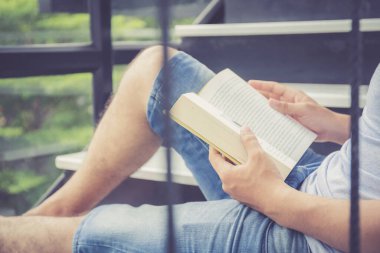  Sıradan kıyafet giyen Asyalı bir iş adamı kitap okuyor.