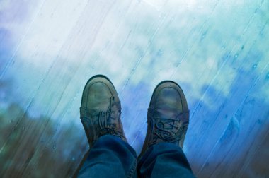 Kahverengi deri ayakkabılar ve yerde duran kot pantolonlar.