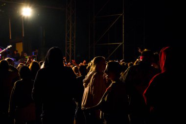 Canlı müzik konseri, gece hayatı ve kalabalık, ayakta durup müzik dinleyen genç yetişkinler..