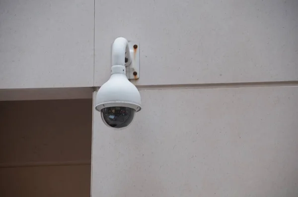 Security CCTV dome camera attached to a white wall near the door