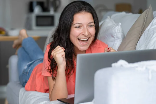 Dívka Ležící Gauči Raduje Když Dívá Laptop Úsměvy — Stock fotografie