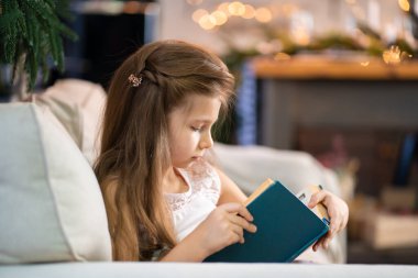 Küçük bir kız ilginç bir kitap okuyor. Çocukların eğitimi ve boş vakitleri
