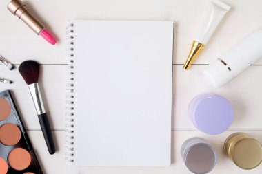 Beyaz ahşap masadaki kozmetik ürünleri ve cilt bakım ürünlerinin üst görünümü   