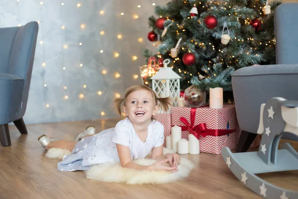 かわいい子供がクリスマスツリーの前に床に横たわる — ストック写真