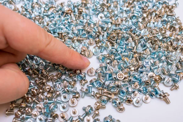 The worker selects screws from a large set for his job