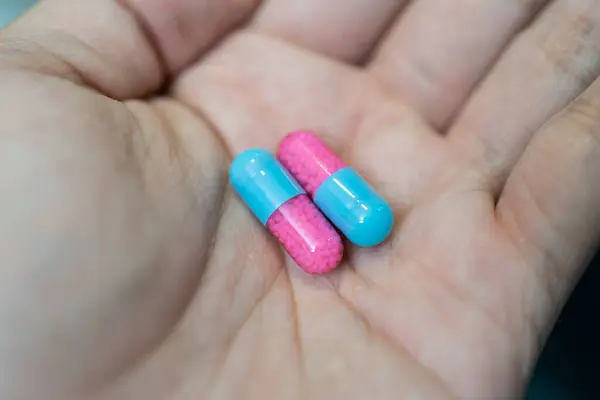 Mano Mostrando Píldora Cápsula Azul Rosa Sobre Fondo Borroso — Foto de Stock