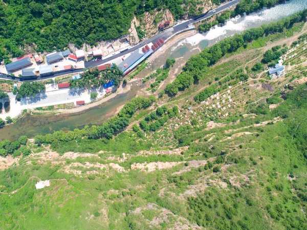Aerial view of small river running next a village in the mountain