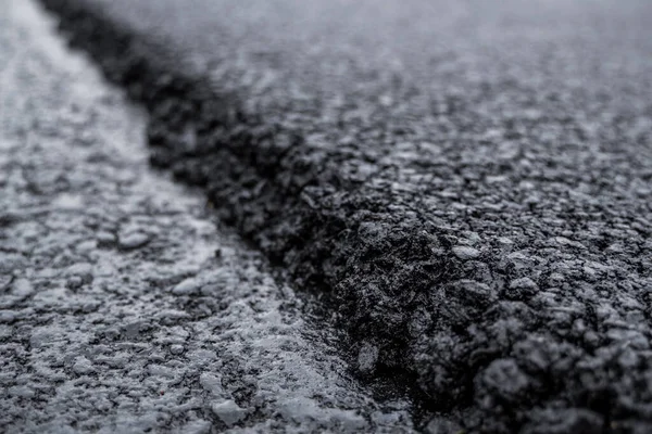 Büyük bir katman taze asfalt. Sığ bir alan derinliğinde asfalt ham madde tabakası. Patenler yeni yolda taze asfalt gibi yuvarlanıyor. Yol yapımı. Yeni bir yol inşaatı.