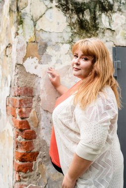 Portrait of a young beautiful caucasian plus size woman standing on the street smiling