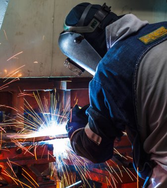 Endüstriyel fabrikada çelikle çalışan kaynakçı