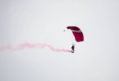 silhouette parachute stunt unfocused and blurry while gliding in the air with red smoke trail during an air exhibition