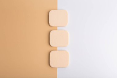 Bej ve pembe arka planda üç makyaj süngeri.