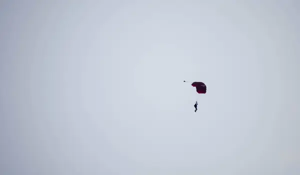 空中で滑っている間にシルエットパラシュートが焦らずぼやけ — ストック写真