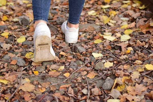 Chodzące Nogi Niebieskich Dżinsach Białych Butach Jesiennych Liściach — Zdjęcie stockowe