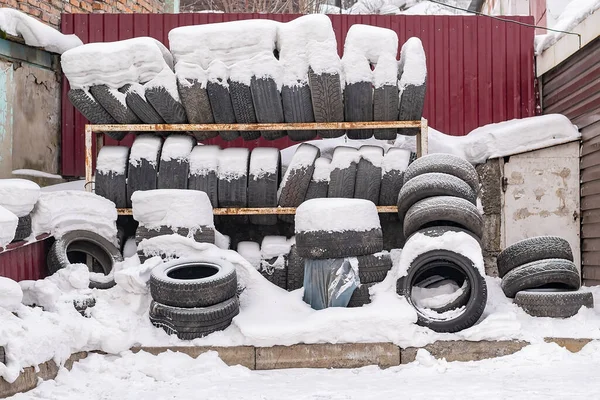 一堆破旧的旧汽车轮胎躺在雪地里 — 图库照片