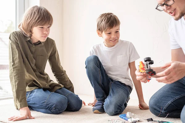 ワークショップでは 若い男の子と教師がロボットカーの構築を楽しんでいます — ストック写真