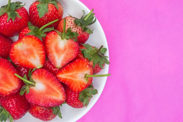 赤いイチゴ食品の背景甘い赤い果実ピンク色の布の質感に赤い果実のハート型の果物の半分プレート — ストック写真