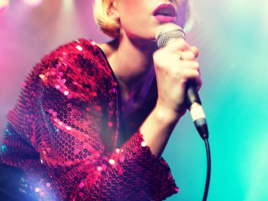 Genç kadın mikrofonla şarkı söylüyor.