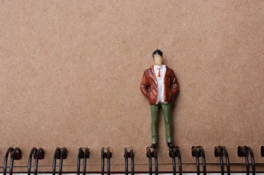 Spiral defterin yanında duran küçük bir adamın biblosu.