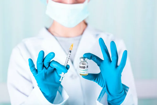 医師または看護師の制服と手袋顔マスク保護を身に着けている研究室で薬を保持バイアルワクチンボトルでCovid 19コロノウイルスワクチンラベル — ストック写真