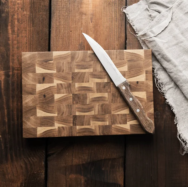 茶色の木の板の上に金属製のキッチンナイフと木製のまな板 — ストック写真