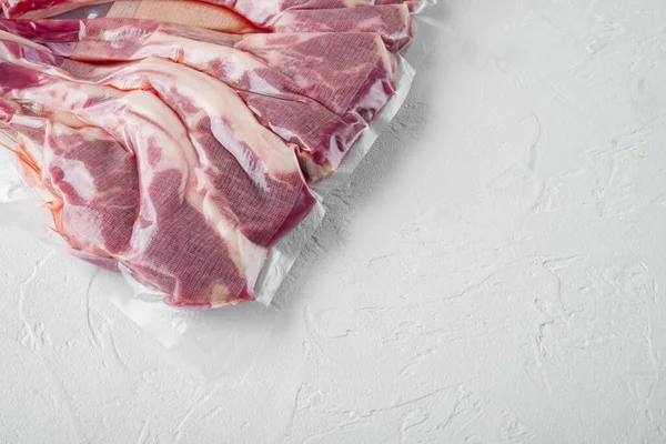 Vacuum sealed fresh lamb chops for sous vide, on white stone background, top view flat lay , with copyspace and space for text