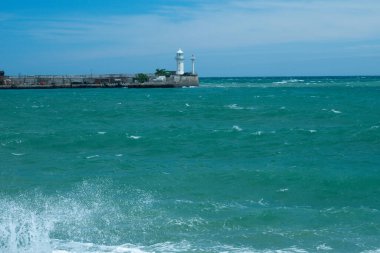 Ufukta beyaz bir deniz feneri olan deniz manzarası.