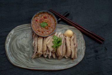 Asian food style marinated steamed chicken (Betong Chickken) and sauce on ceramic plate. Serving chilled as an appetizer.