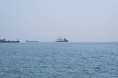 Bulutlu bir günde açık denizin havadan çekilmiş fotoğrafı. Mavi gökyüzü, uzaktaki gemiler ve sınırsız ufuk.