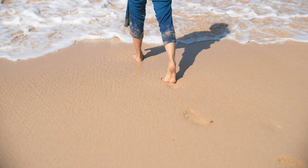 海滩上沙滩上的脚印 走到海里的女人 — 图库照片