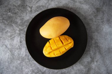 Siyah tabakta taze sarı mango meyvesi.
