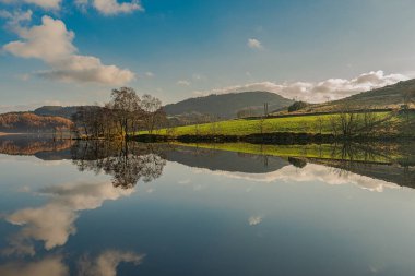 Göl üzerindeki sonbahar manzarası suda yansıyor.
